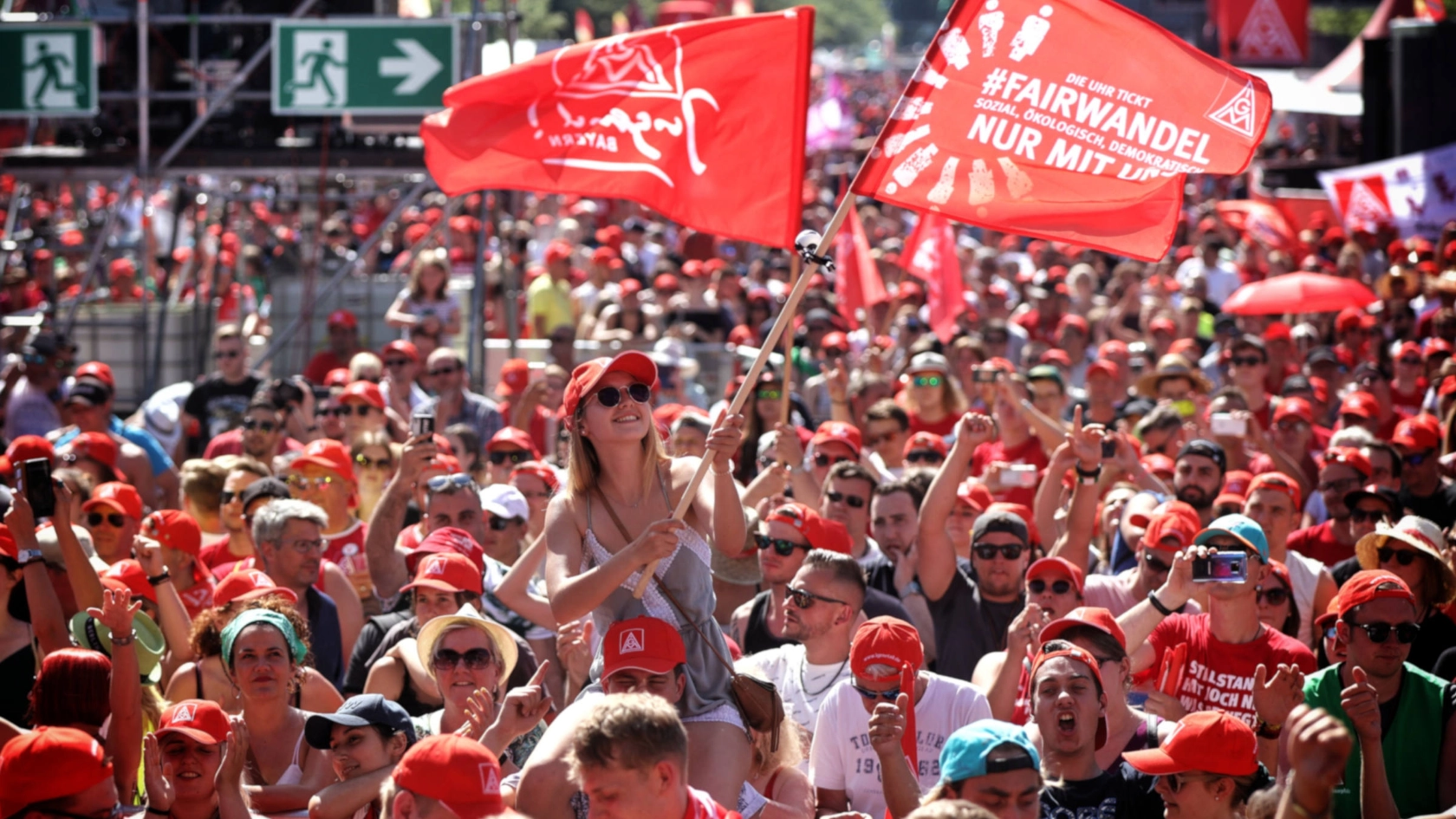 Eine junge Frau schwenkt eine Fahne auf der FairWandel-Kundgebung der IG Metall in Berlin.